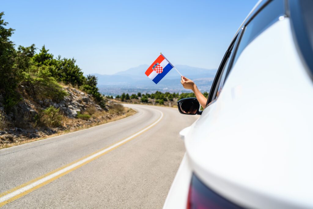 driving in Croatia with a Croatian flag waving outside of the car window